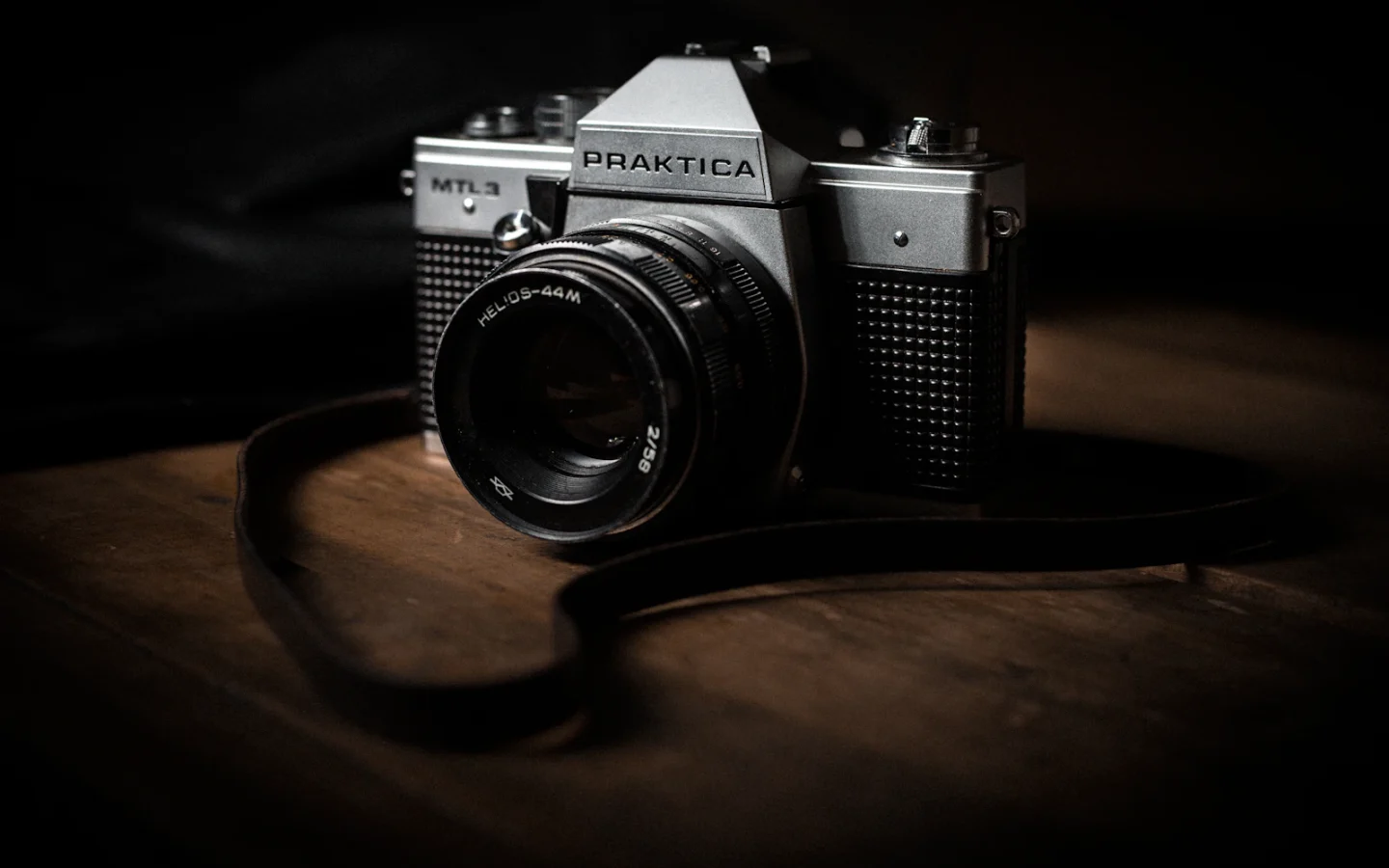 Máy ảnh Pentax đen bạc trên mặt bàn gỗ nâu
