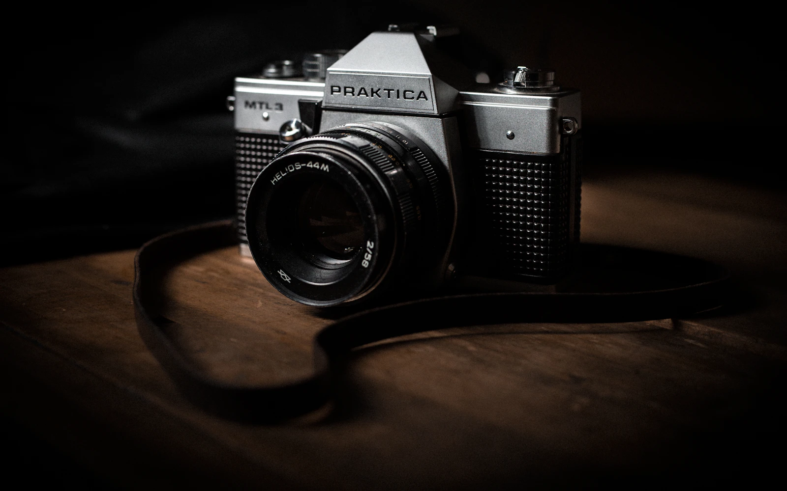 Máy ảnh Pentax đen bạc trên mặt bàn gỗ nâu